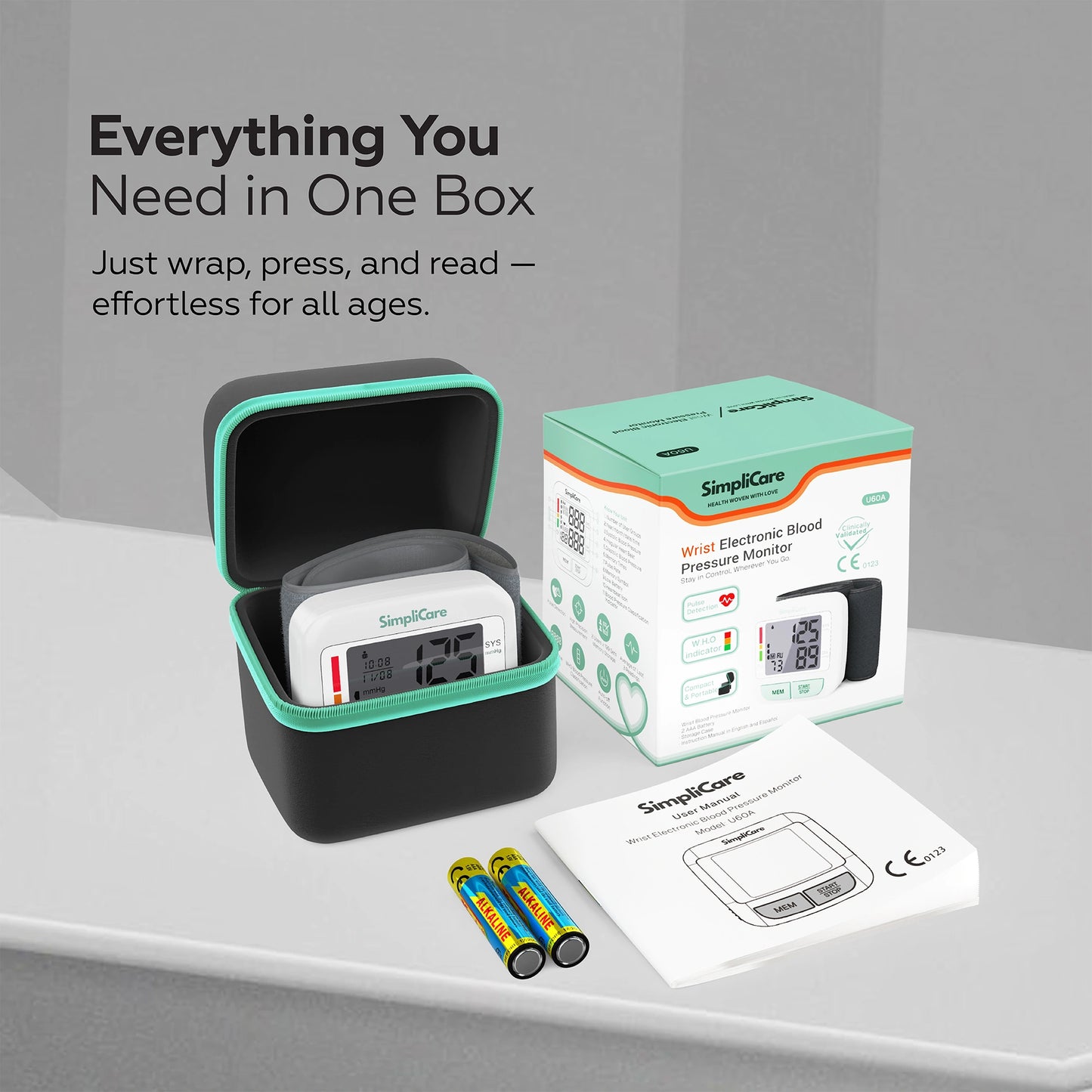 SimpliCare blood pressure monitor with carrying case, batteries, and user manual on a gray surface.